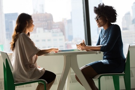 two women seated at a table having a discussion